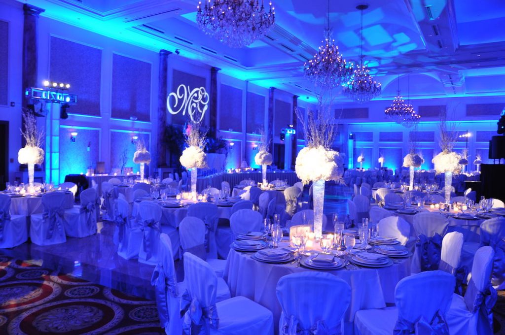 Banquet room illuminated with blue LED uplighting and custom monogram gobo